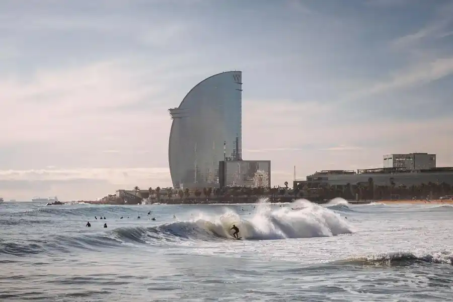 Plage de la Barceloneta avec le W Hotel en arrière-plan et surfeurs dans les vagues
