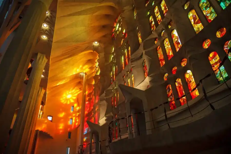 Vitraux colorés de la Sagrada Familia projetant des lumières orange et rouge sur les murs intérieurs