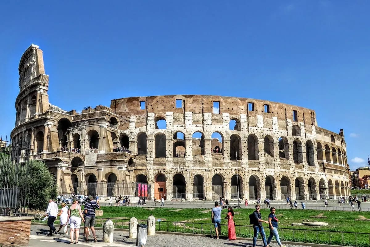 Turistas visitando el Coliseo de Roma bajo el sol de verano